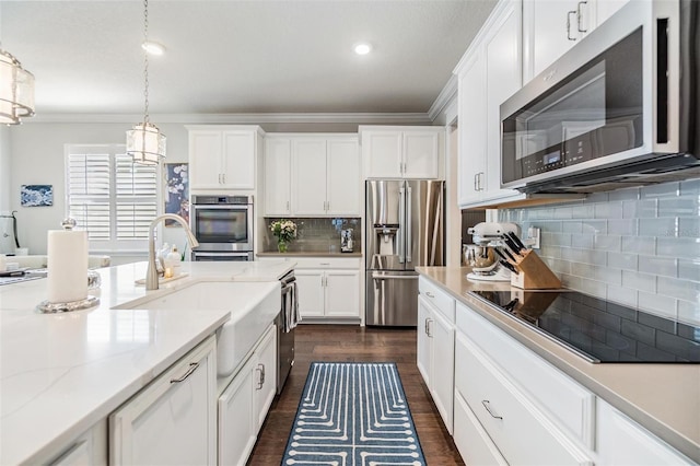 kitchen with hanging light fixtures, dark wood-type flooring, decorative backsplash, appliances with stainless steel finishes, and white cabinetry