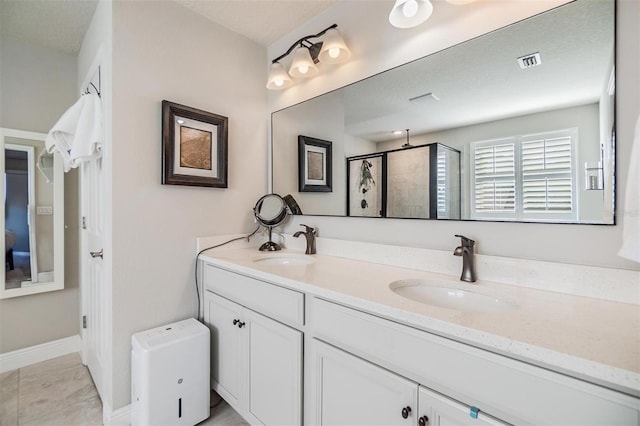 full bathroom featuring double vanity, a stall shower, visible vents, and a sink