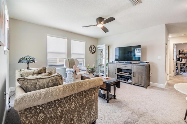 living area with visible vents, light carpet, baseboards, and a ceiling fan