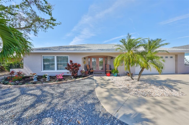 ranch-style house with stucco siding, french doors, an attached garage, and concrete driveway