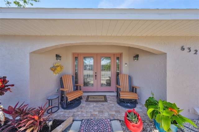 entrance to property with french doors, stucco siding, and a patio area