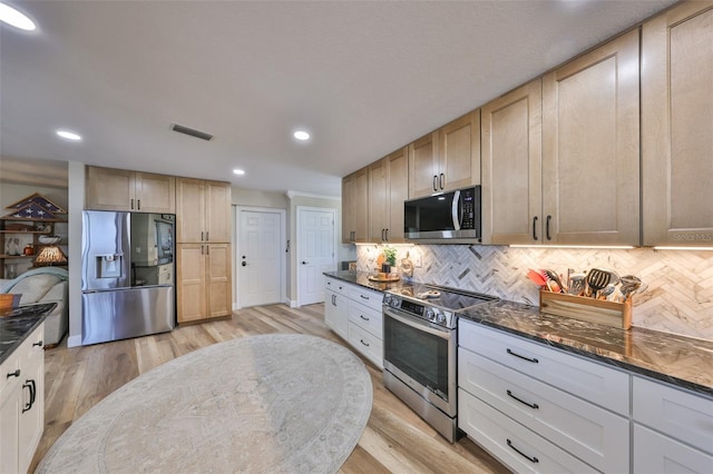 kitchen featuring stainless steel appliances, backsplash, visible vents, and dark stone counters