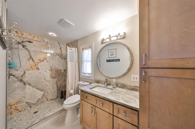 full bathroom featuring vanity, toilet, a shower stall, and a textured ceiling