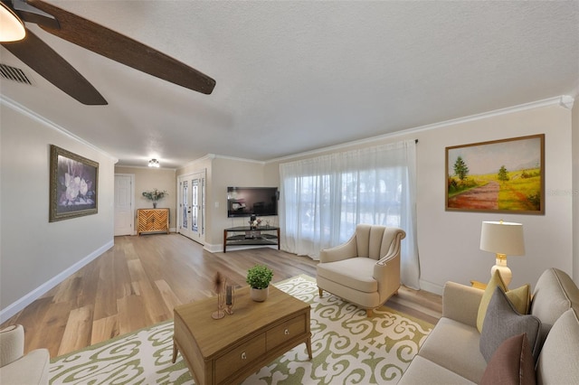 living room with light wood-type flooring, visible vents, and crown molding