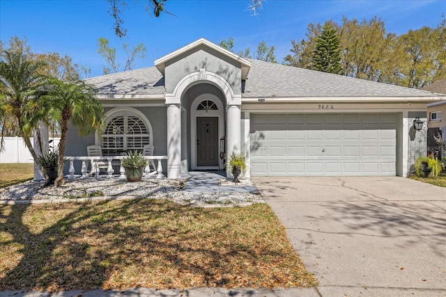 view of front facade with roof with shingles, stucco siding, a porch, a garage, and driveway