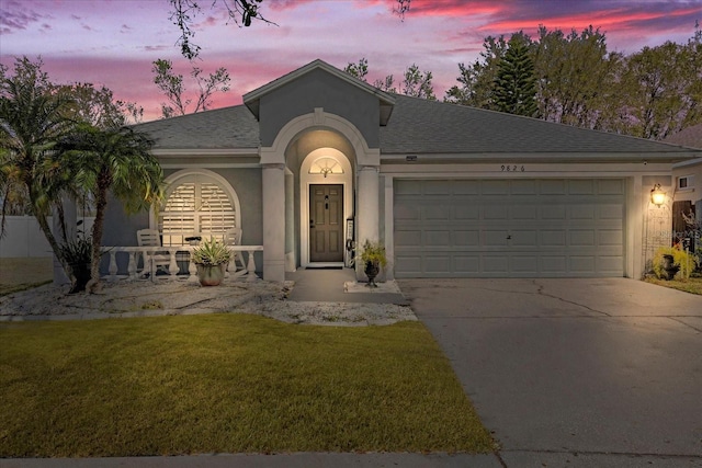 ranch-style house with a garage, concrete driveway, stucco siding, roof with shingles, and a front yard