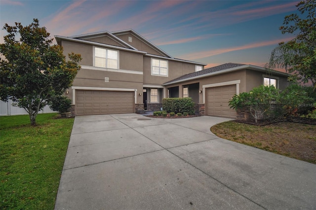 traditional home featuring stone siding, concrete driveway, a front lawn, and stucco siding