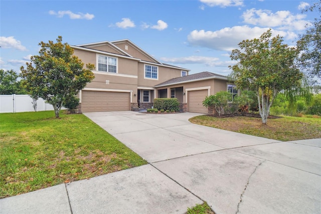 traditional-style home with concrete driveway, stone siding, stucco siding, fence, and a front yard