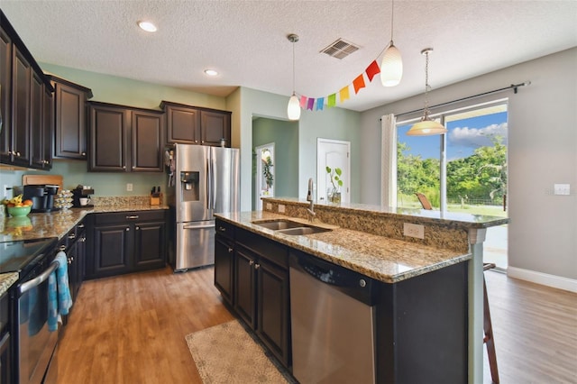 kitchen with light stone counters, a sink, visible vents, appliances with stainless steel finishes, and light wood finished floors