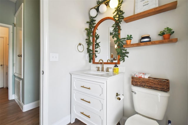 bathroom featuring toilet, wood finished floors, vanity, and baseboards