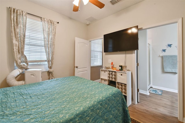 bedroom featuring a ceiling fan, visible vents, baseboards, and wood finished floors