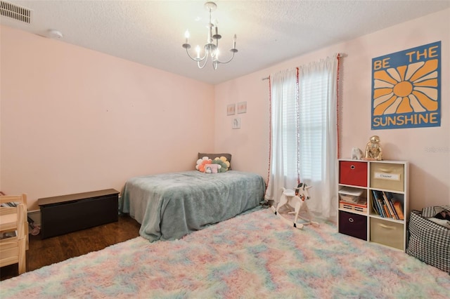 bedroom with a chandelier, visible vents, and a textured ceiling