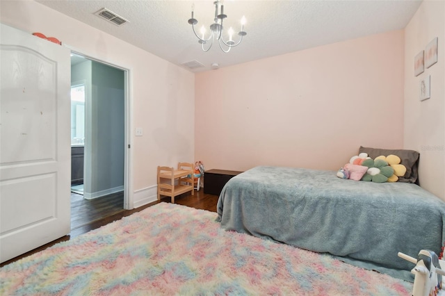 bedroom with visible vents, a notable chandelier, a textured ceiling, and wood finished floors