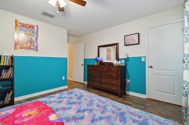 bedroom featuring baseboards, visible vents, a ceiling fan, wood finished floors, and a textured ceiling