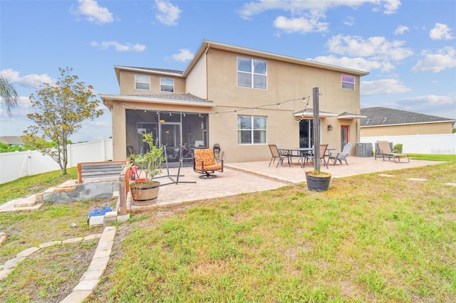 back of house featuring a yard, a patio, stucco siding, a sunroom, and a fenced backyard