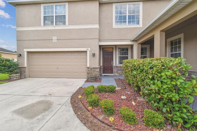 view of front of house featuring stone siding, driveway, an attached garage, and stucco siding