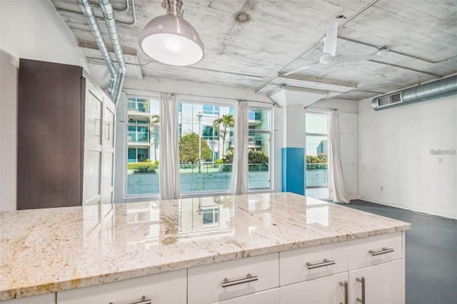 kitchen featuring light stone countertops, finished concrete floors, visible vents, and white cabinets