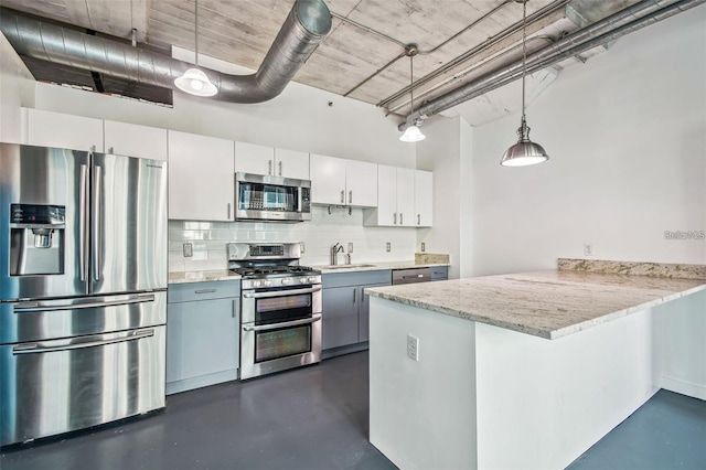 kitchen with decorative light fixtures, a peninsula, a sink, stainless steel appliances, and backsplash