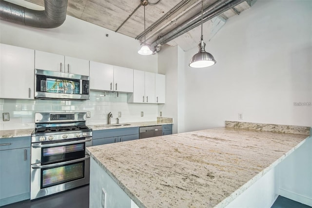 kitchen with decorative backsplash, a peninsula, stainless steel appliances, white cabinetry, and a sink