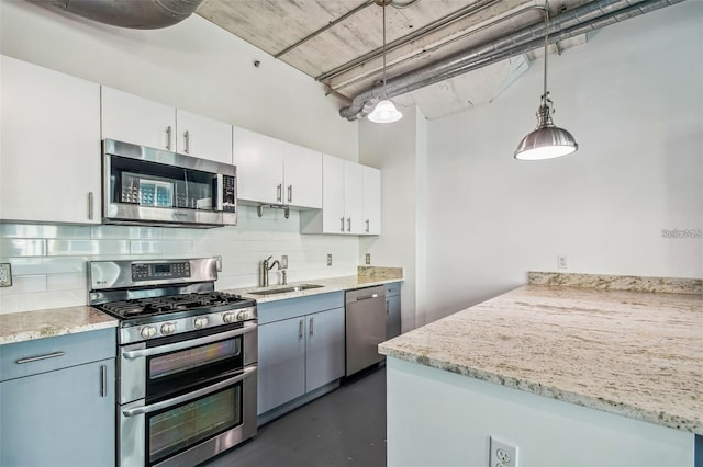 kitchen with stainless steel appliances, a sink, white cabinetry, hanging light fixtures, and backsplash