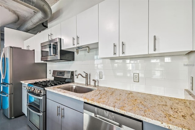 kitchen featuring appliances with stainless steel finishes, backsplash, a sink, and light stone counters