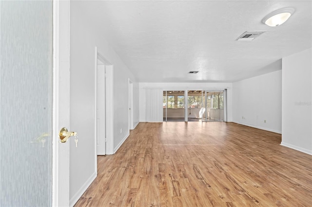 unfurnished living room with light wood-type flooring, visible vents, and baseboards