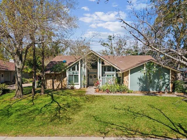 mid-century home featuring a front yard and stone siding