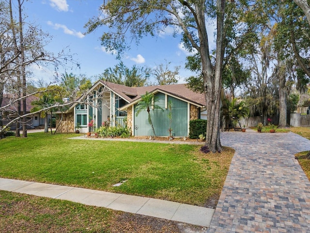 mid-century home featuring a front yard and decorative driveway