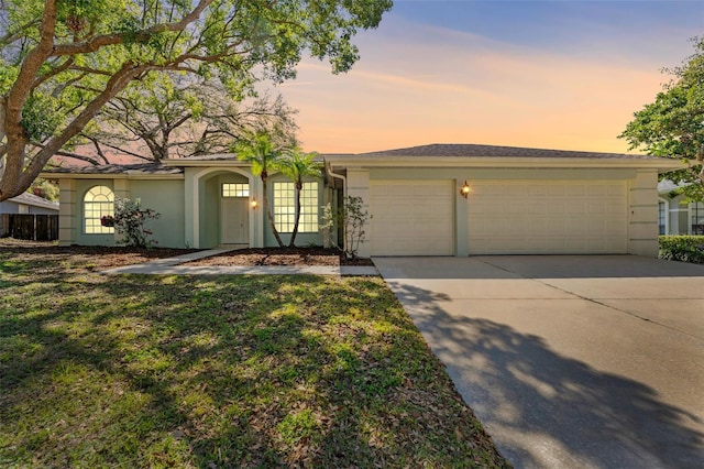 ranch-style house with driveway, a front lawn, an attached garage, and stucco siding