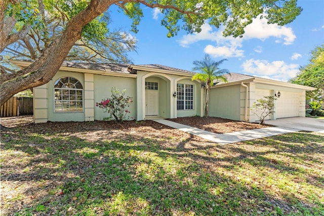 view of front of home featuring a garage, driveway, fence, and stucco siding