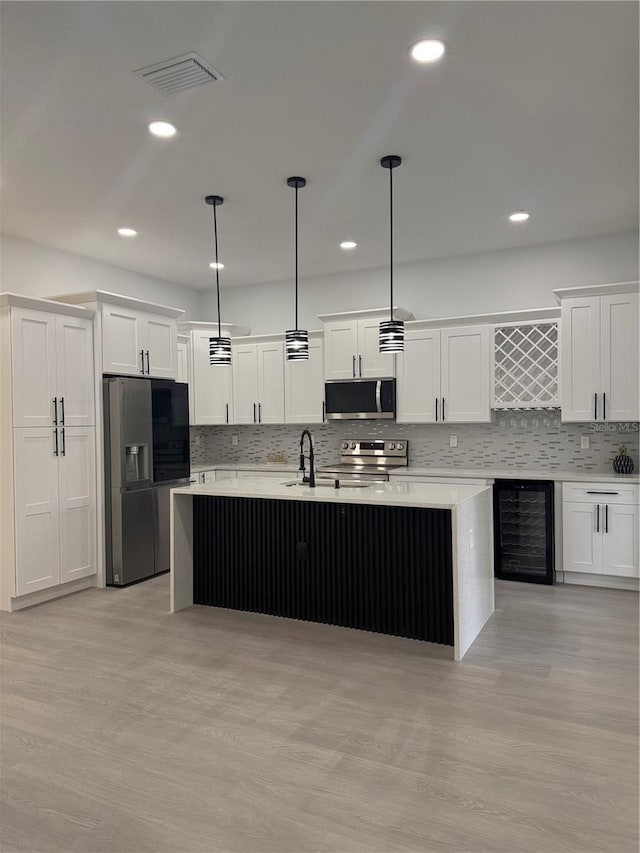 kitchen featuring visible vents, a sink, wine cooler, appliances with stainless steel finishes, and white cabinets