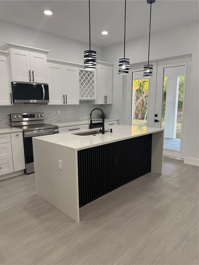 kitchen with backsplash, stainless steel appliances, an island with sink, and a sink