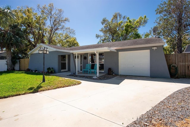 single story home featuring a garage, concrete driveway, a front lawn, and stucco siding