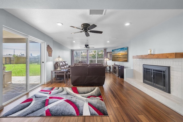 living room featuring recessed lighting, a fireplace, visible vents, baseboards, and wood-type flooring