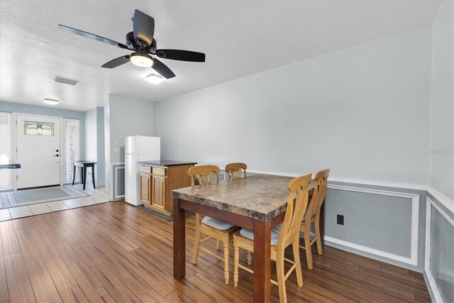 dining room featuring a textured ceiling, ceiling fan, wood finished floors, and visible vents