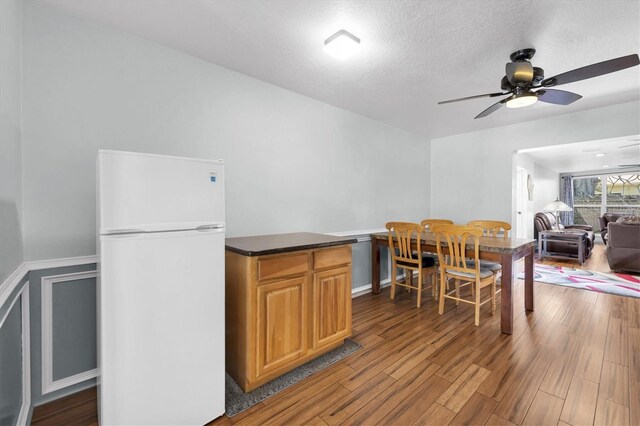 dining room with a textured ceiling, a ceiling fan, and wood finished floors