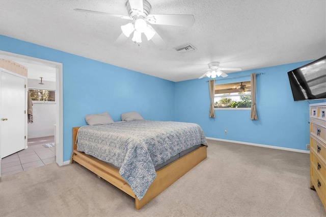 carpeted bedroom featuring baseboards, visible vents, a ceiling fan, ensuite bathroom, and a textured ceiling