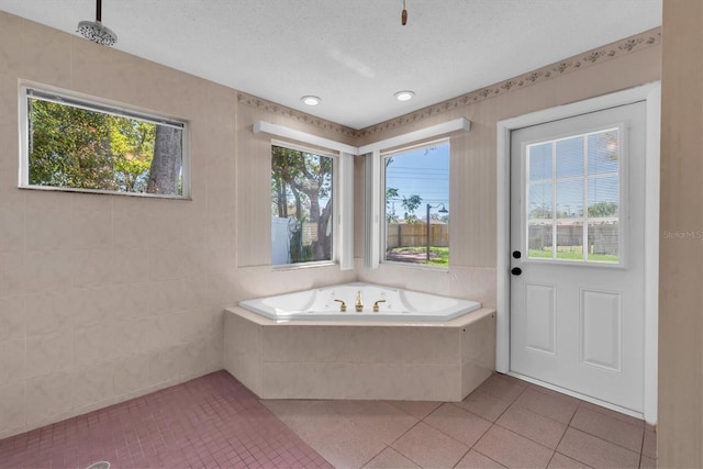 bathroom with a textured ceiling, a garden tub, and tile patterned floors