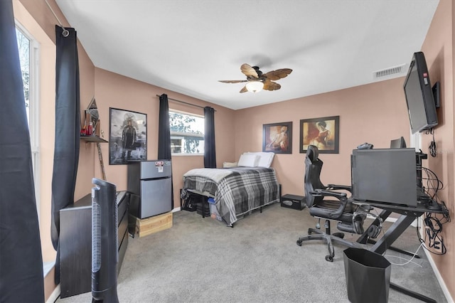 carpeted bedroom featuring baseboards, freestanding refrigerator, visible vents, and a ceiling fan