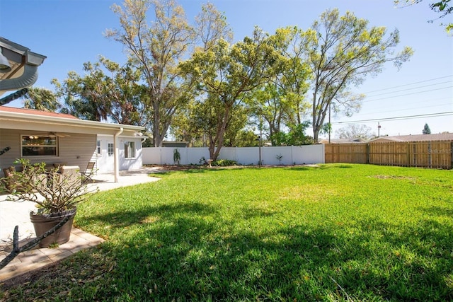 view of yard with a ceiling fan, a fenced backyard, and a patio