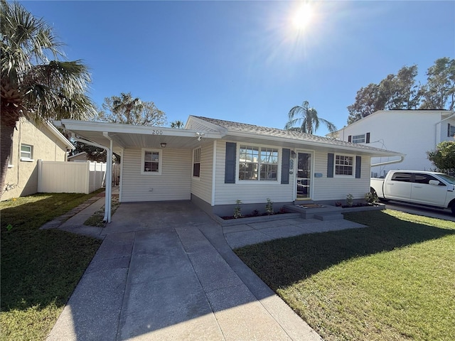 view of front facade with an attached carport, concrete driveway, fence, and a front lawn