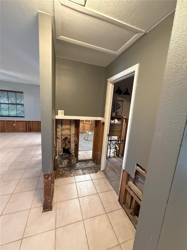 interior space with light tile patterned floors and a wainscoted wall