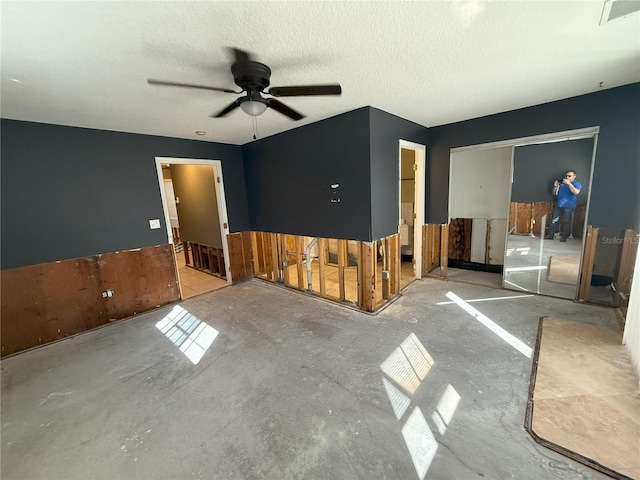 empty room with a textured ceiling, ceiling fan, concrete floors, and visible vents