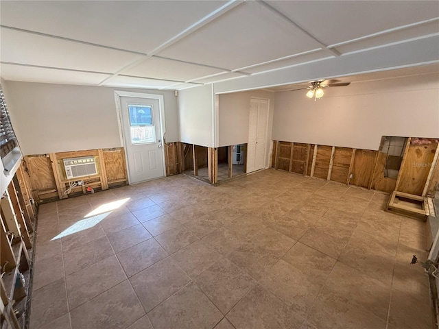 unfurnished room featuring a wall unit AC, a wainscoted wall, and a ceiling fan