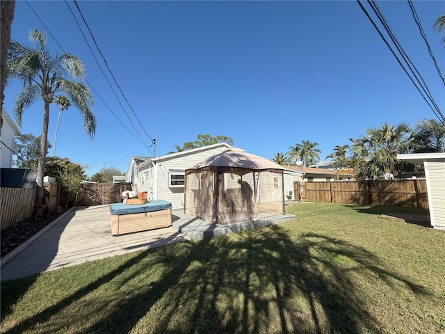 rear view of property with a patio area, a fenced backyard, a lawn, and a gazebo