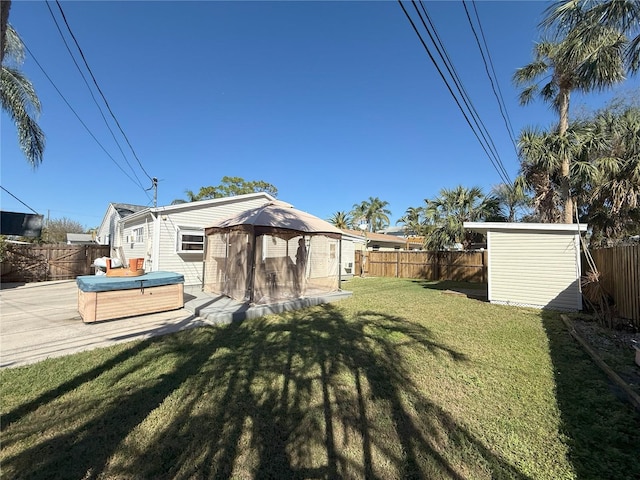 view of yard featuring hot tub deck surround, a patio, a fenced backyard, and a gazebo