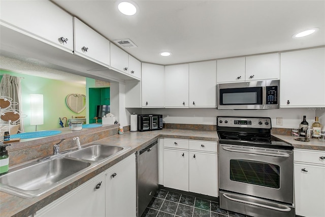 kitchen featuring stainless steel appliances, white cabinets, visible vents, and a sink