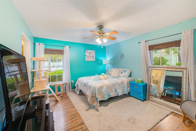 bedroom with ceiling fan, a textured ceiling, and wood finished floors