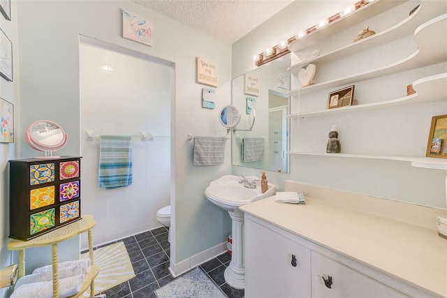 bathroom featuring toilet, tile patterned flooring, a textured ceiling, a walk in shower, and a sink