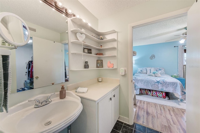 bathroom featuring a ceiling fan, ensuite bath, tile patterned flooring, a textured ceiling, and a sink